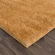 Close-up of Heavenly Solid Mustard Plush Rug with thick dark gold plush pile on wooden floor